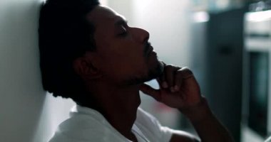Frustrated black man sitting on home floor feeling concerned, african person suffering from mental illness, in a position of weakness
