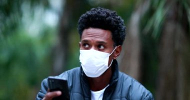 Casual candid black african man looking at smartphone device during pandemic