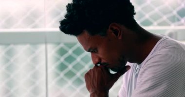 Pensive African man pondering about decision with hand in chin