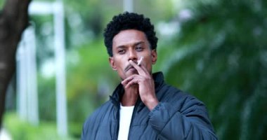 Mixed race portrait man smoking cigarette tobacco outdoors, unhealthy habit