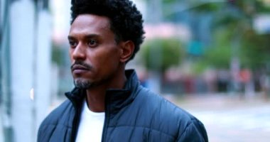 Confident man walking in city. Positive Person of african descent walks in urban sidewalk
