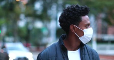 African American man walking in city wearing face mask. Black person walking forward in downtown