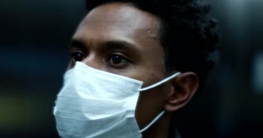 Black african man wearing covid mask looking at mirror close-up face