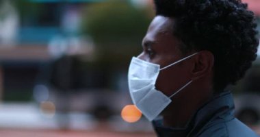 African person walking in city downtown wearing surgical mask outside