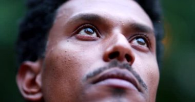 Contemplative man closing eyes. Close-up face portrait of mixed race person meditating outside