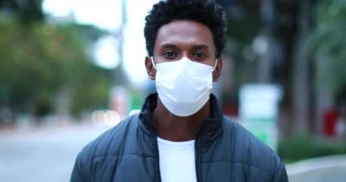Confident African American wearing face mask walking in city downtown