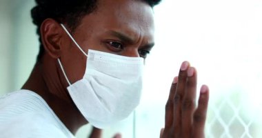 Black man during quarantine wearing virus mask looking out