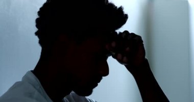 Depressed man sitting on floor. Sad unhappy person holding his forehead suffering from mental illness