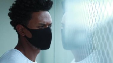African american looking out window wearing outbreak mask