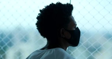 African man wearing black covid-19 mask during quarantine at home