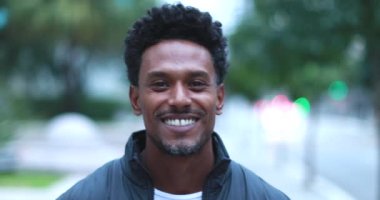 Happy confident african man walking forward in city smiling
