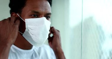 Black african man removing face mask indoors at home
