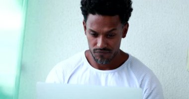 Pensive Mixed race black man working in front of computer laptop thinking