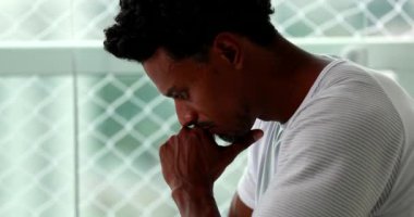 Pensive African man pondering about decision with hand in chin