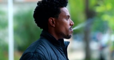 Man exhaling smoke from cigarette outdoors