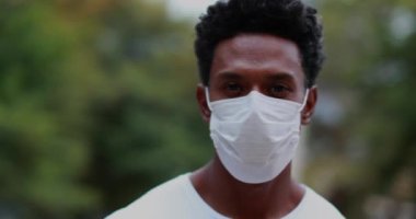 African American standing looking to camera wearing covid-19 surgical mask, pandemic outbreak prevention