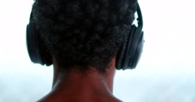 Back of man listening to music wearing headphones
