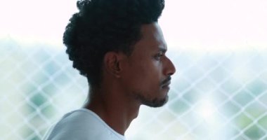 Thoughtful black African man standing by window at home apartment