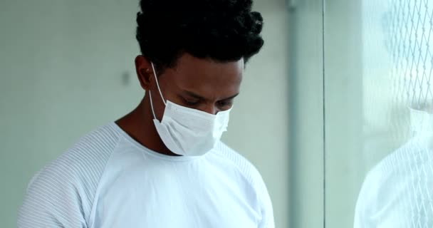 Pensive Black Man Using Smartphone Wearing Covid Virus Mask Indoors — ストック動画