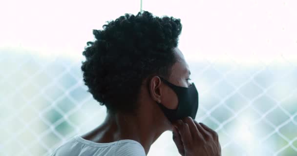African Man Adjusting Covid Mask Home Looking Out Apartment Window — Stock video