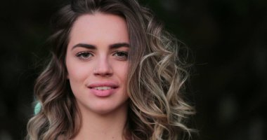 Flirtatious beautiful blonde hispanic young woman looking to camera smiling