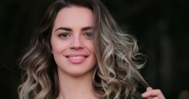 Flirtatious beautiful blonde hispanic young woman looking to camera smiling