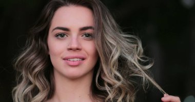 Flirtatious beautiful blonde hispanic young woman looking to camera smiling