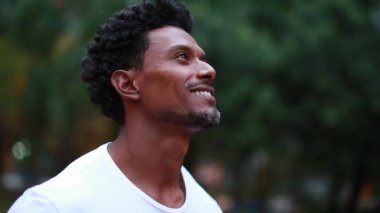 Black guy standing outside in nature looking at the sky, circling around 360 degrees african man standing