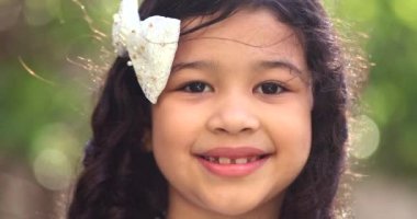 Hispanic child girl smiling portrait face close-up adjusting hair