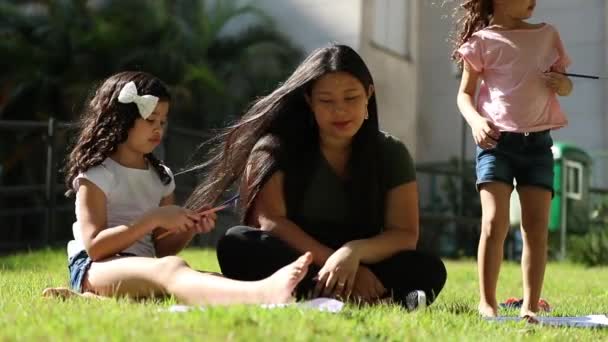Asian Mother Sitting Outdoors Ethnically Diverse Little Daughters Studying Together — Video