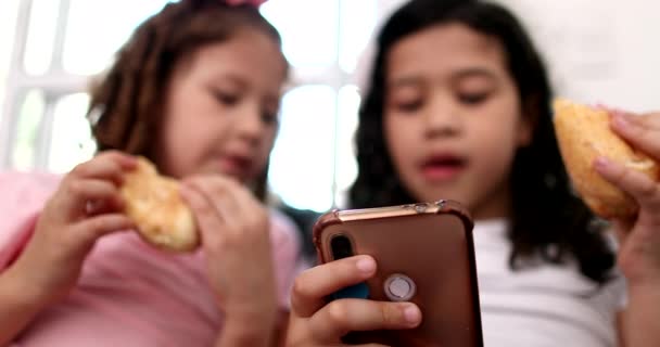 Γενιά Μικρά Κορίτσια Που Χρησιμοποιούν Κινητό Τηλέφωνο Ενώ Τρώνε Σνακ — Αρχείο Βίντεο