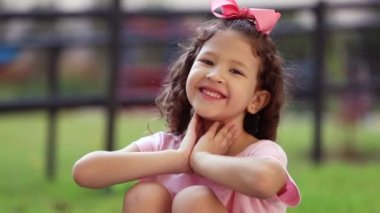 Cute mixed race little girl child posing to camera outside, kid blowing kiss