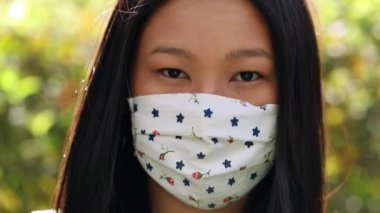 Asian young woman wearing covid-19 face mask looking at camera