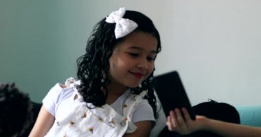 Little girl siblings sharing cellphone screen with sister