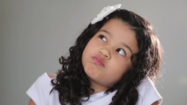 Pensive thoughtful hispanic asian little girl child thinking and smiling