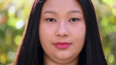 Asian young woman looking at camera outside. Portrait ethnically diverse female