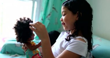 Cute mix race little girl child playing with black doll