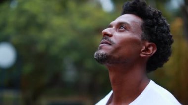 Young man face looking at the sky in meditation and contemplation with hope and faith