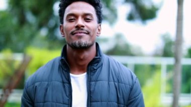 Confident mixed race black man walking forward to camera. African american descent person portrait outdoors