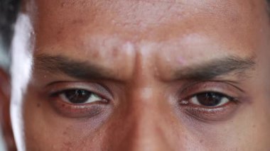 Skeptical person close-up eyes reaction, black african person eye looking to camera surprised