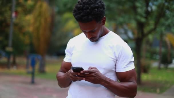 Афроамериканець Друкує Мобільному Телефоні Парку Чоловік Стоїть Надворі Тримає Смартфон — стокове відео
