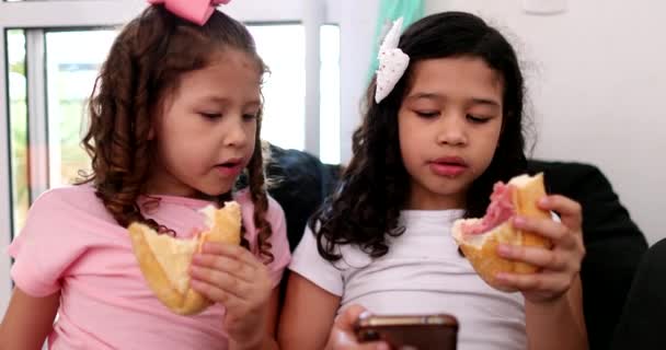 Две Маленькие Девочки Загипнотизированные Сотовым Телефоном Время Еды Сэндвич Закуски — стоковое видео