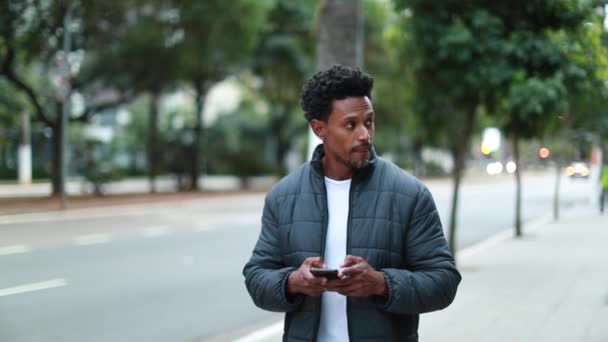 Чорний Чоловік Перетинає Вулицю Дивлячись Мобільний Телефон Місті Африканці Ходять — стокове відео