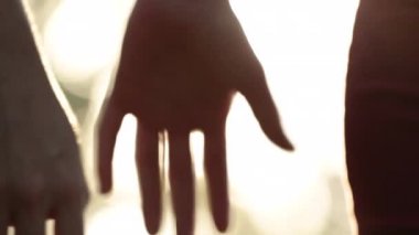 Joining hands together held tight with sunlight flare in the background shining