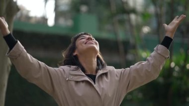 Religious thankful young woman raising arms in air celebrating life in prayer to God. Spiritual person feeling HOPE and FAITH feeling FREE