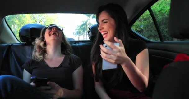 现实生活中的朋友们一起在出租车的后座上笑着拿着手机 查看留言 两个女友与在线内容互动的坦诚片段 — 图库视频影像
