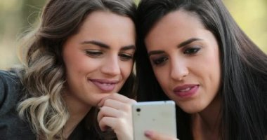 Authentic friends together outdoors checking cellphone