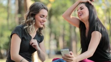 Candid Girlfriends looking at their cellphone outdoors on social media