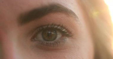 Macro close-up of young woman eyes in the sunlight with flare, opening and closing eyes meditating and contemplation