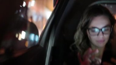Woman typing on cellphone at night in the passenger back seat of car